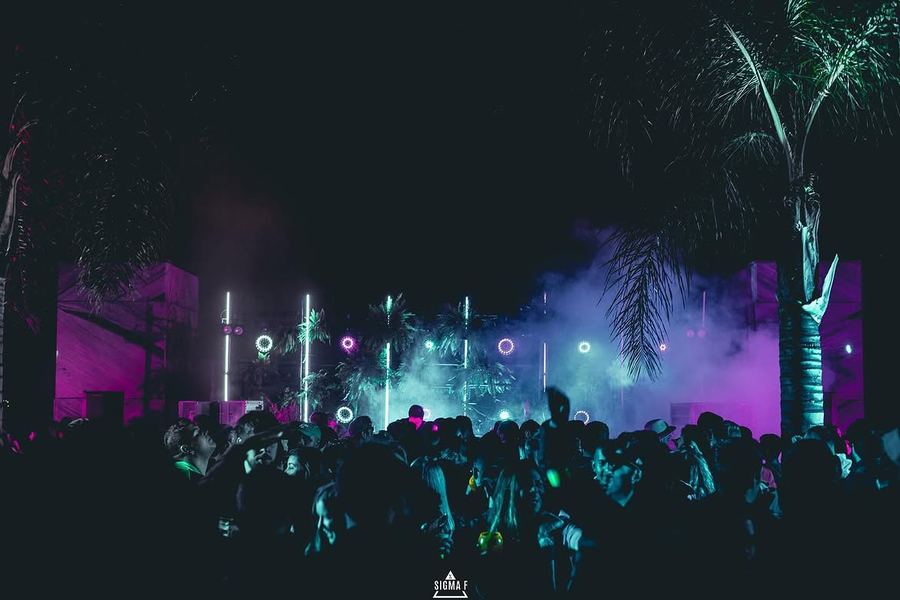 Show com iluminação e fumaça sob palmeiras