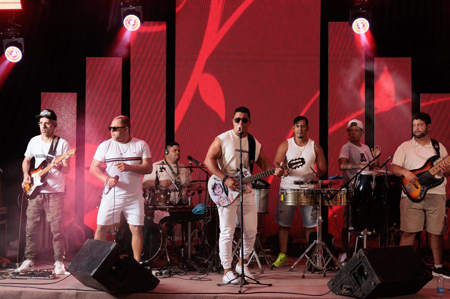 Banda se apresentando no palco com iluminação vermelha